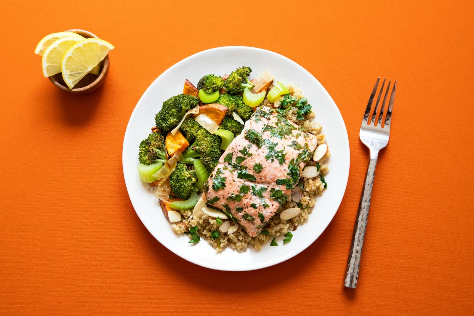 Baked salmon over quinoa with roasted broccoli and lemon, top-down editorial shot